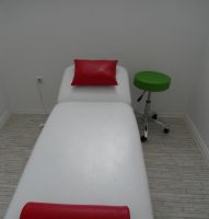 Rotes Kunstlederkissen mit Knierolle auf einer Behandlungsliege